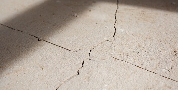 Cracks in the concrete cement screed on the floor after repair. The concrete surface texture is covered with web cracks. Gray stone background